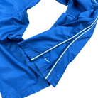Detailansicht des unteren Beins mit weißem Reißverschluss und Swoosh-Logo der hellblauen Nike Trackpants in Größe L